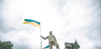 Soldier on tank holding Ukrainian flag