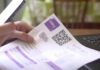 Hand holding utility bill with QR code