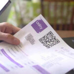 Hand holding utility bill with QR code