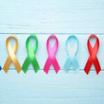 Colorful awareness ribbons on light wooden background.