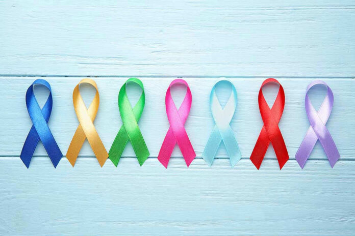 Colorful awareness ribbons on light wooden background.