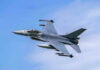 Jet fighter flying through clear blue sky.
