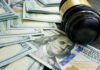 Gavel and hundred dollar bills on table.