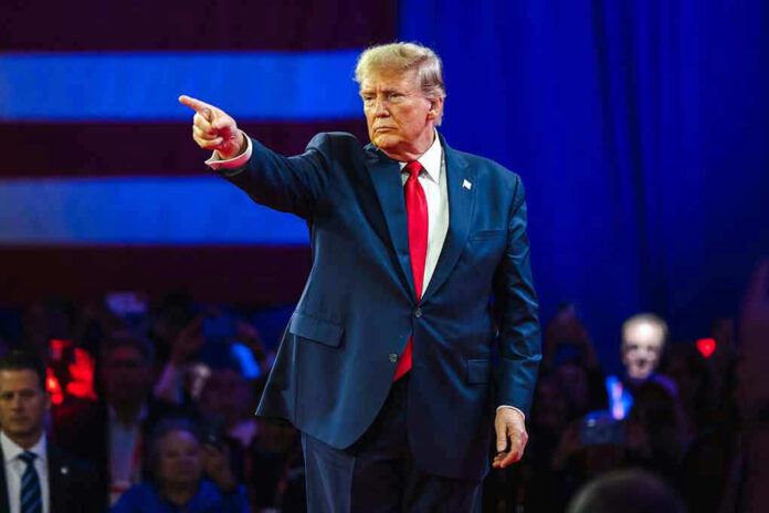 2430065795 Person in suit pointing during a public event.