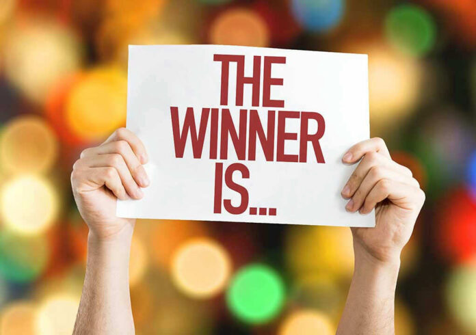 322328513 Hands holding a sign reading The Winner Is