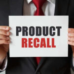 "Product Recall" sign held by person in suit.