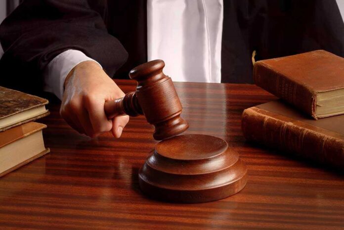 shutterstock_2080475.jpg A judges hand holding a gavel over a wooden desk with law books