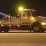 Tow truck with flashing lights parked at night