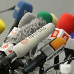 A collection of various microphones arranged for a press conference