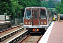 Metro train arriving at a station surrounded by greenery