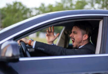Man yelling inside a car, looking frustrated.