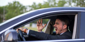 Man yelling inside a car, looking frustrated.