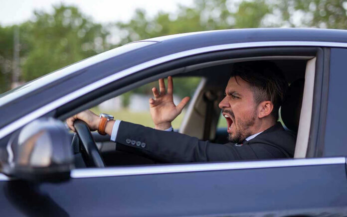 Man yelling inside a car, looking frustrated.