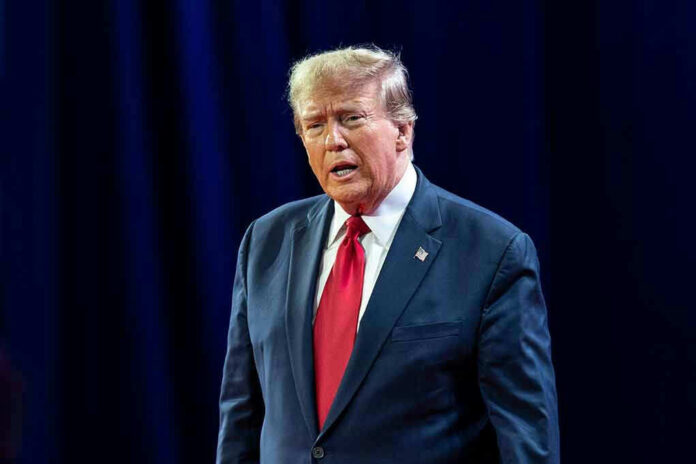 2429741167 Man in suit with red tie speaking on stage.