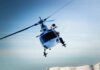A helicopter flying over a mountainous landscape under a blue sky