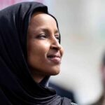 A woman wearing a black hijab looking thoughtfully into the distance