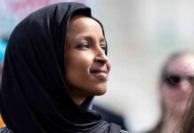 A woman wearing a black hijab looking thoughtfully into the distance
