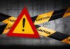 Warning sign with caution tape against a concrete background