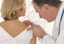 Doctor examining a patients skin with a magnifying glass
