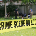 Yellow crime scene tape blocking grassy area.