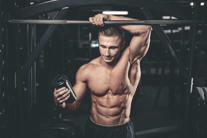 644740183 Muscular man in gym holding a shaker bottle