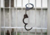 Handcuffs hanging on a barred window.