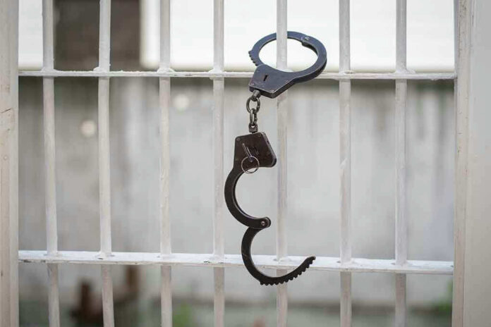 Handcuffs hanging on a barred window.