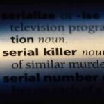 Close-up of a dictionary page showing the definition of 'serial killer'