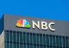 NBC logo displayed on a corporate building against a blue sky