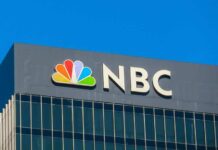 NBC logo displayed on a corporate building against a blue sky