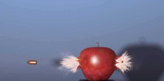 A red apple being struck by a bullet, showing an explosion effect