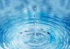 Close-up of water droplets creating ripples in a blue water surface