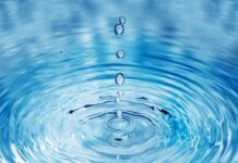 Close-up of water droplets creating ripples in a blue water surface