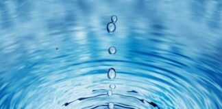 Close-up of water droplets creating ripples in a blue water surface