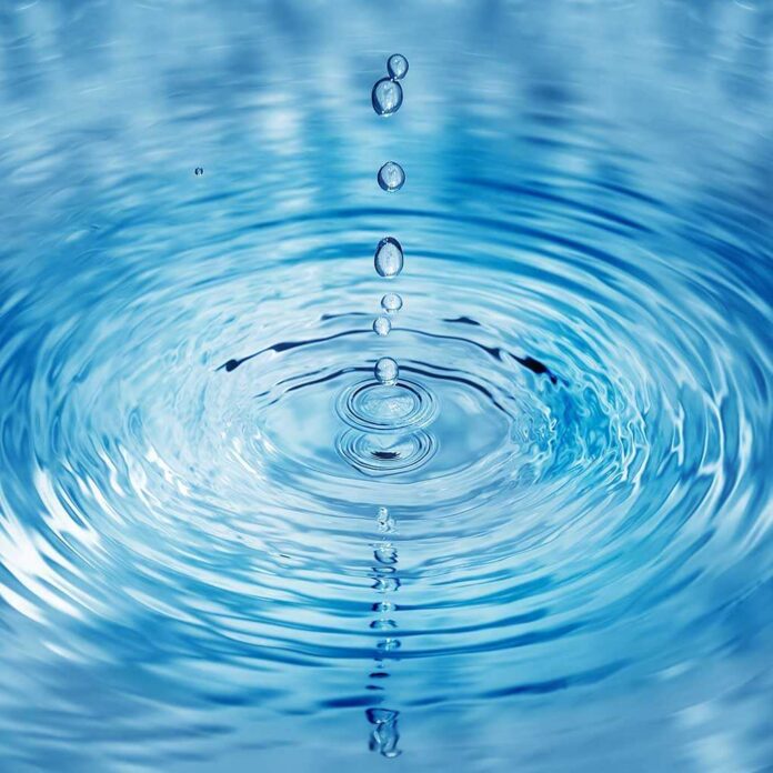 Close-up of water droplets creating ripples in a blue water surface
