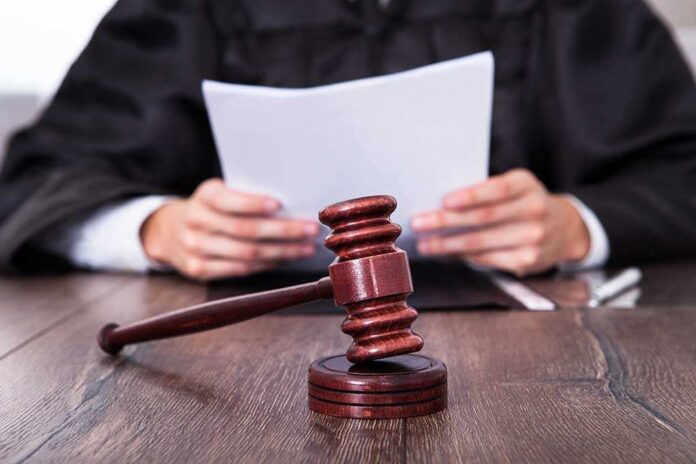 shutterstock_164106293.jpg A judge holding documents with a gavel in the foreground