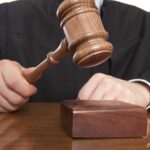 A judge holding a gavel above a wooden block