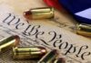 Historic Gun Rights Case — Unpredictable Outcome Awaits Close-up of bullets surrounding a historical document with the phrase We the People