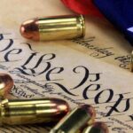 Historic Gun Rights Case — Unpredictable Outcome Awaits Close-up of bullets surrounding a historical document with the phrase We the People