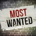 FBI’s BOMBSHELL — America’s Most Wanted REVEALED A weathered poster displaying the words MOST WANTED on a brick wall