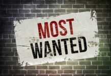 FBI’s BOMBSHELL — America’s Most Wanted REVEALED A weathered poster displaying the words MOST WANTED on a brick wall