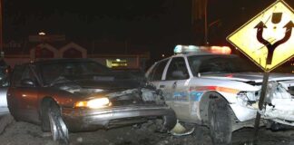 A damaged car and a police vehicle involved in a nighttime accident