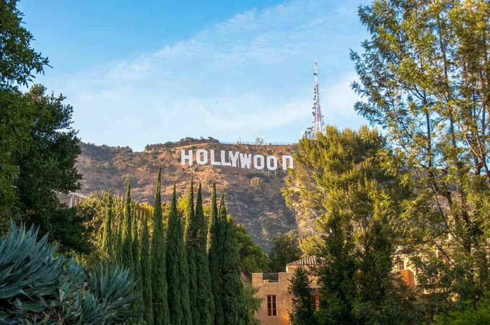 Hollywood sign on hill surrounded by trees and buildings.
