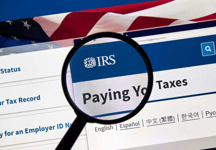 1383312209 Magnifying glass over IRS website for paying taxes.