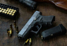 Blackhawks Jersey Killer UNLEASHES 20 Gunshots Handgun with ammunition, magazine, and rifle on wooden table.