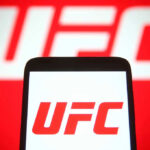 UFC Star AXED After Match-Fixing Allegation UFC logo on phone screen and background.