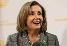 Pelosi FINALLY QUITS — It Is So ABOUT TIME! Smiling woman in plaid blazer with pearl necklace.