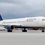 Marine Hero Booted — Airline Sparks Fury Delta Airlines airplane on airport runway, cloudy sky.