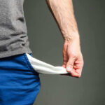 $100,000 Now Poverty? Shocking Reality Check Person pulling out empty pocket from shorts.