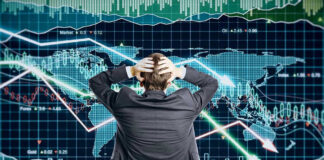 Person in front of falling stock market graph.